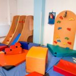 Salle de motricité avec toboggan, mur d'escalade et coussins de motricité